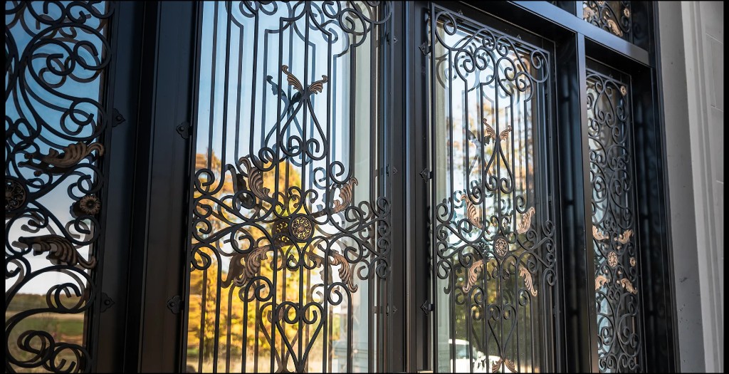 Wrought iron door with decorative scrollwork, glass panels, and bronze accents